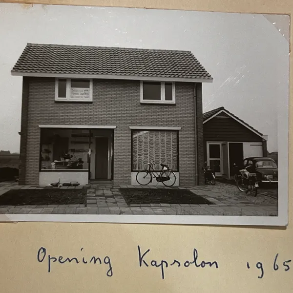 Albumpagina met een foto van het nieuwe pand en het bijschrift 'Opening Kapsalon 1965'