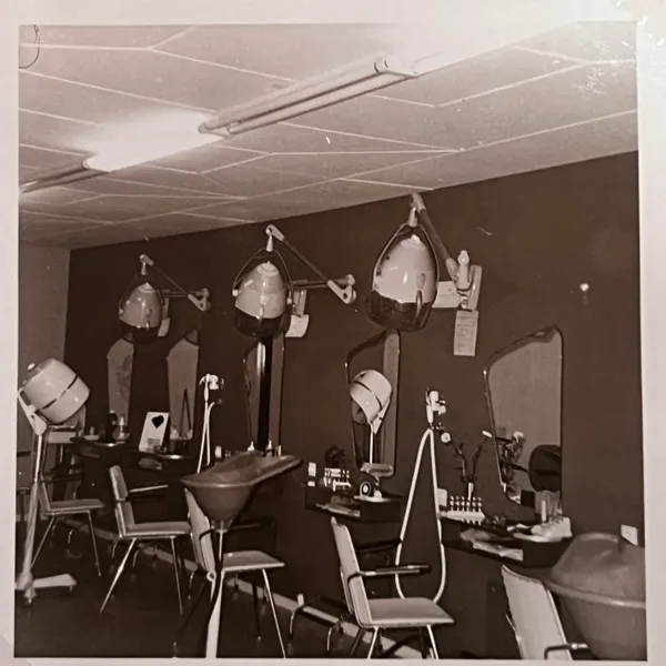 De kappersstoelen met droogkappen langs de spiegelwand