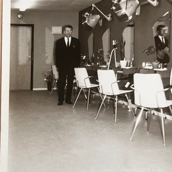 Een man in pak staat in de nieuwe salon tussen de kappersstoelen